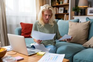 Adult woman reviewing paperwork on her laptop at home while preparing for an ADHD evaluation in Colorado Springs.